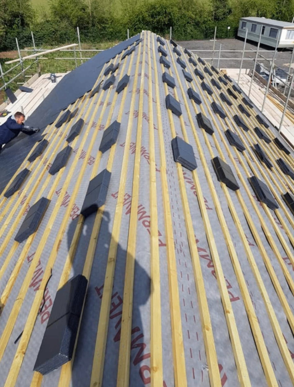 Roofer installing slate tiles on a new roof in the Midlands